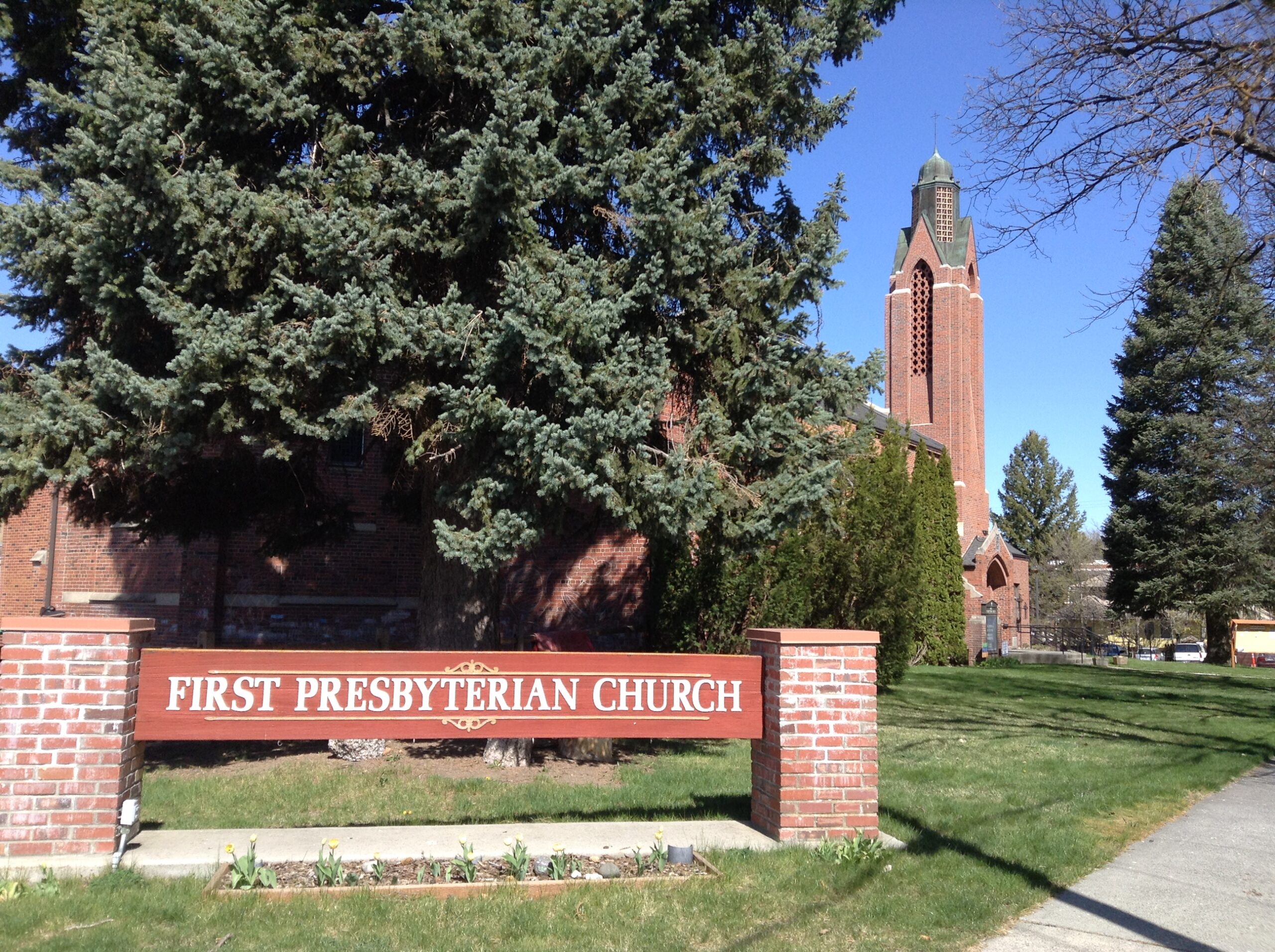 A sign reading "First Presbyterian Church" with the church steeple visible in the background.